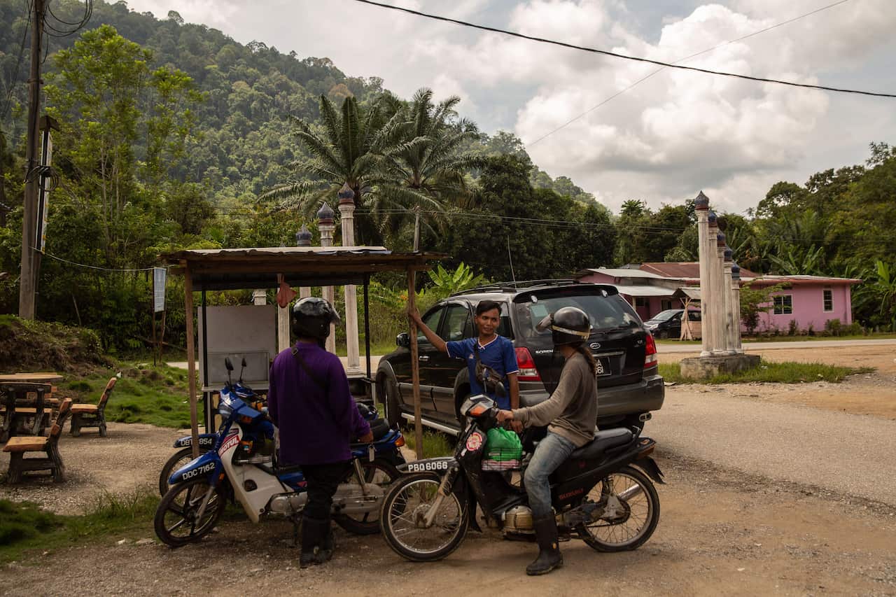 People park their motorbikes at the entrance to Gua Musang, Malaysia, where Ayu, an 11-year-old child bride lives.