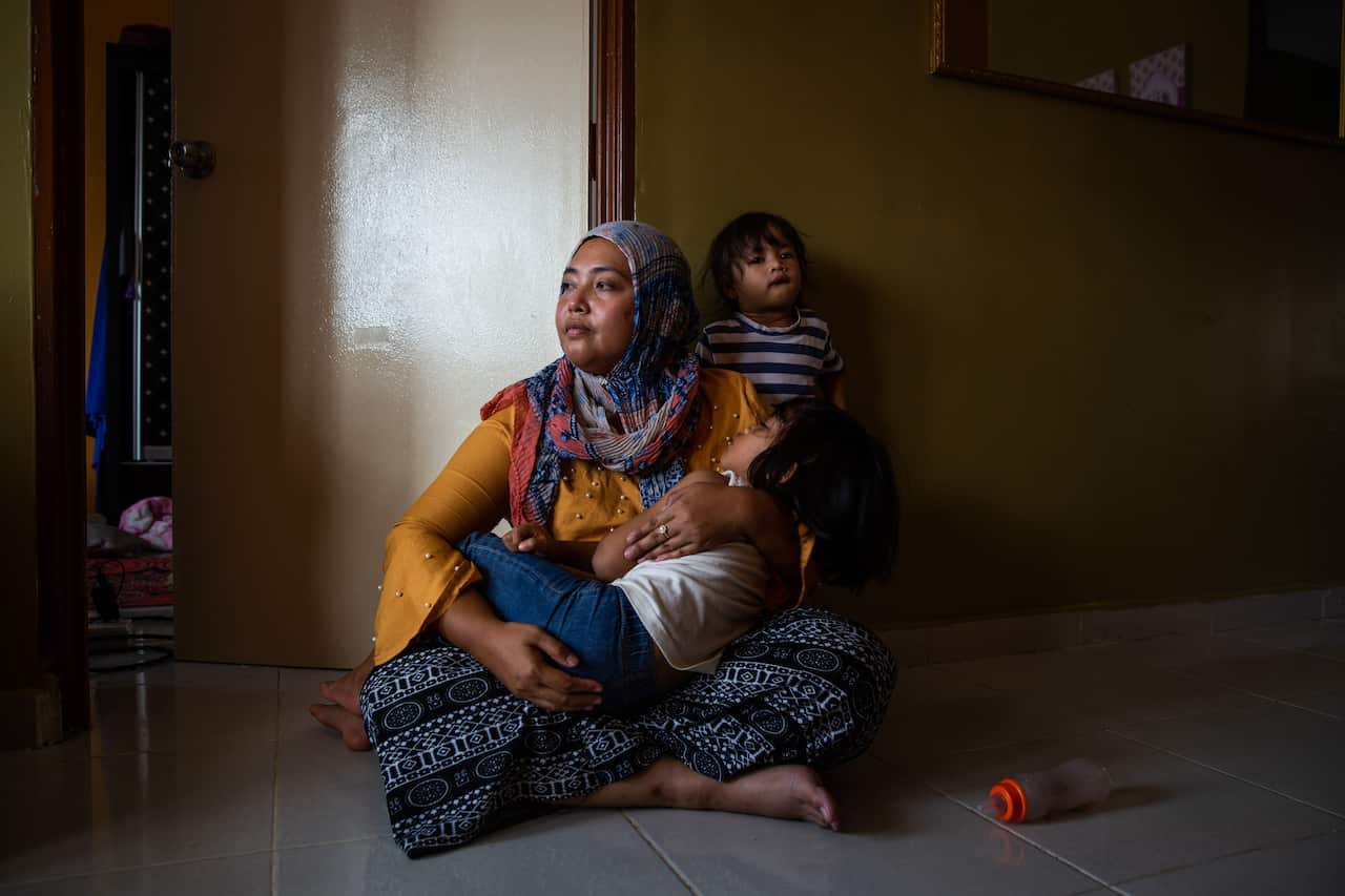 Siti Noor Azila, the second wife of Che Abdul Karim Che Abdul Hamid, sits with her two daughters in her family's home in Gua Musang, Malaysia.
