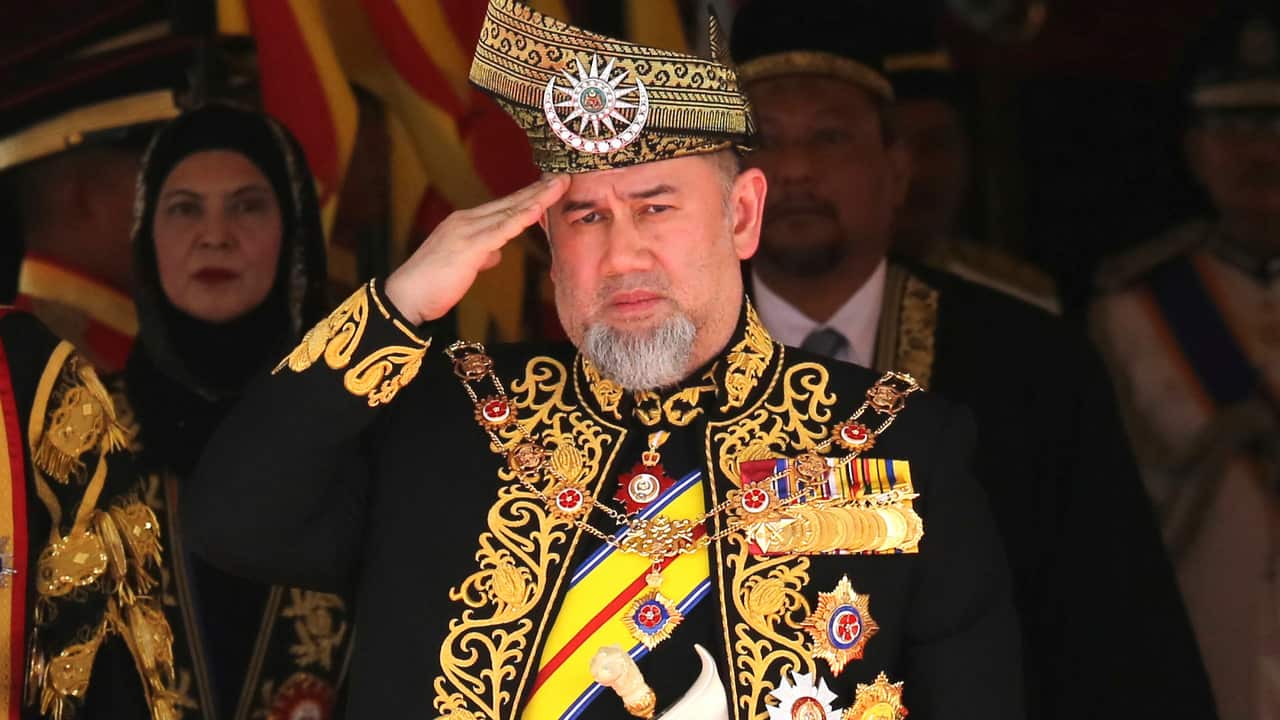 Malaysian King Sultan Muhammad V salutes during the national anthem at the opening of the 14th parliament session.