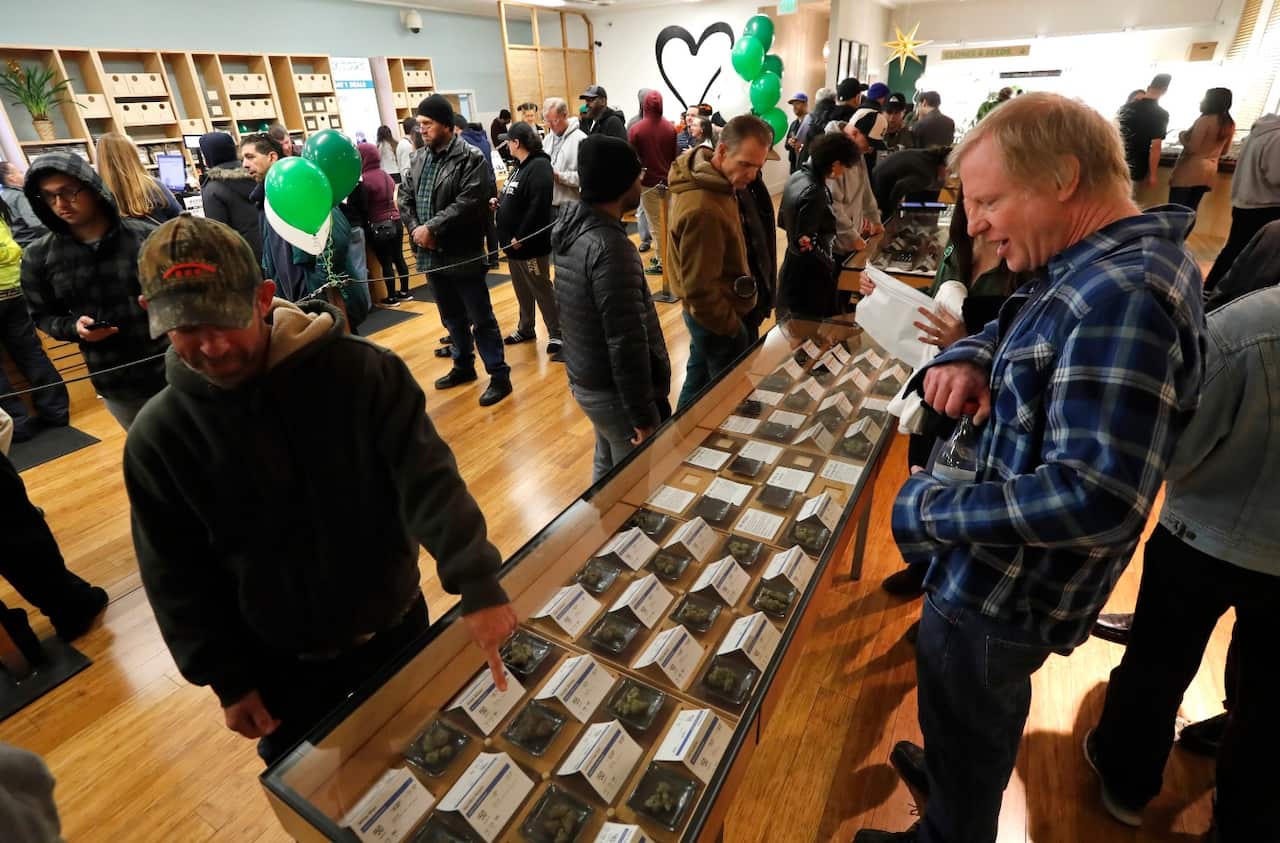 Customers check out cannabis samples on display while waiting in line at the Harborside cannabis dispensary in Oakland, California, USA (AAP)