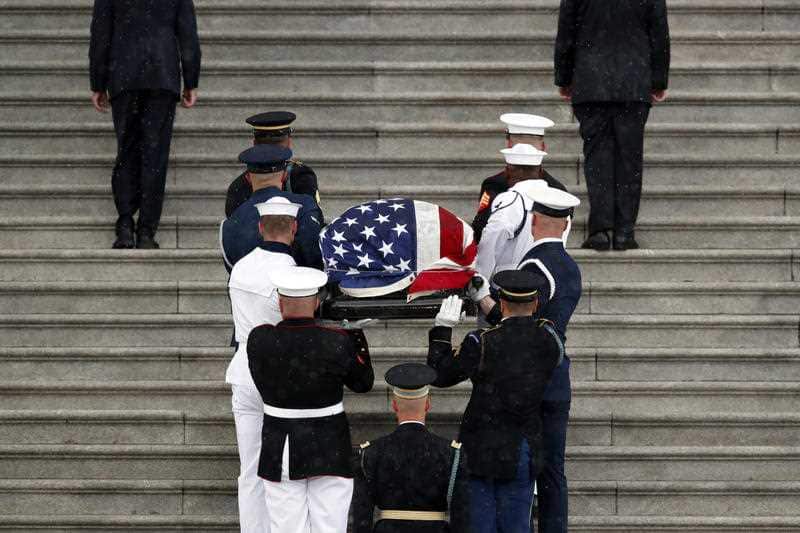 An honour guard of soldiers, sailor, marines and airmen carry the senator's casket.