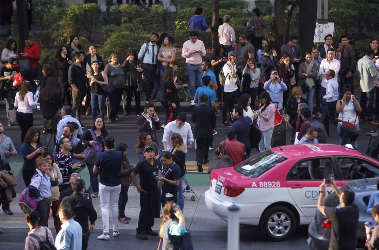 People wait outside their offices and vehicles after an earthquake, in Mexico City, Mexico, 16 February 2018. 