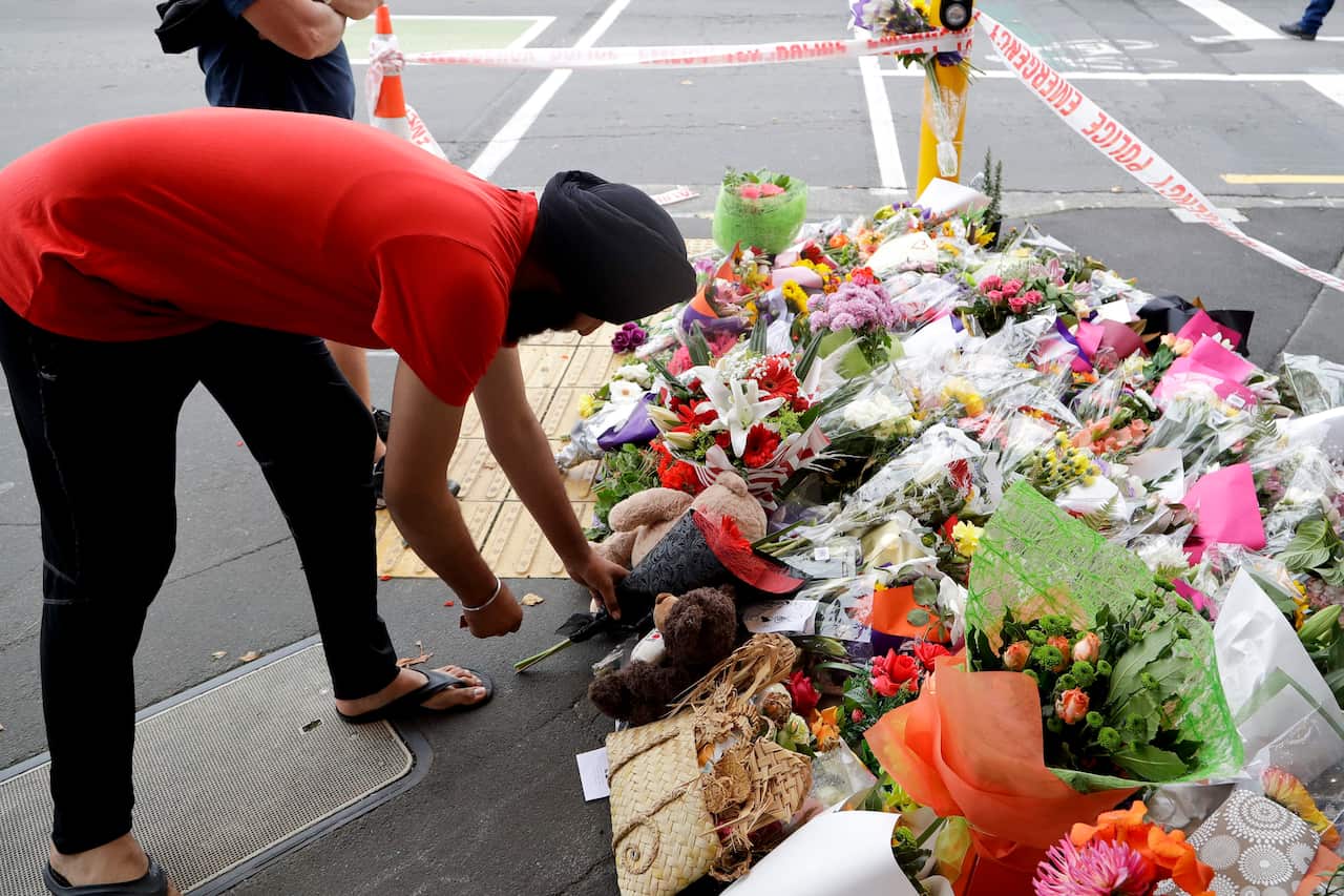 A man places flowers at a makeshift memorial near the Masjid Al Noor mosque in Christchurch, New Zealand, Saturday, March 16, 2019, where one of the two mass shootings occurred. (AP Photo/Mark Baker)