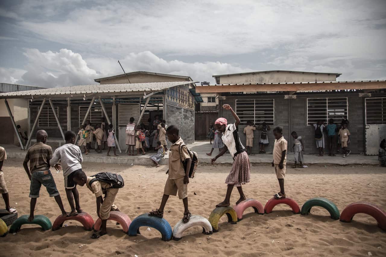 Students play outside new school classrooms made out of plastic bricks in Abidjan, Ivory Coast.