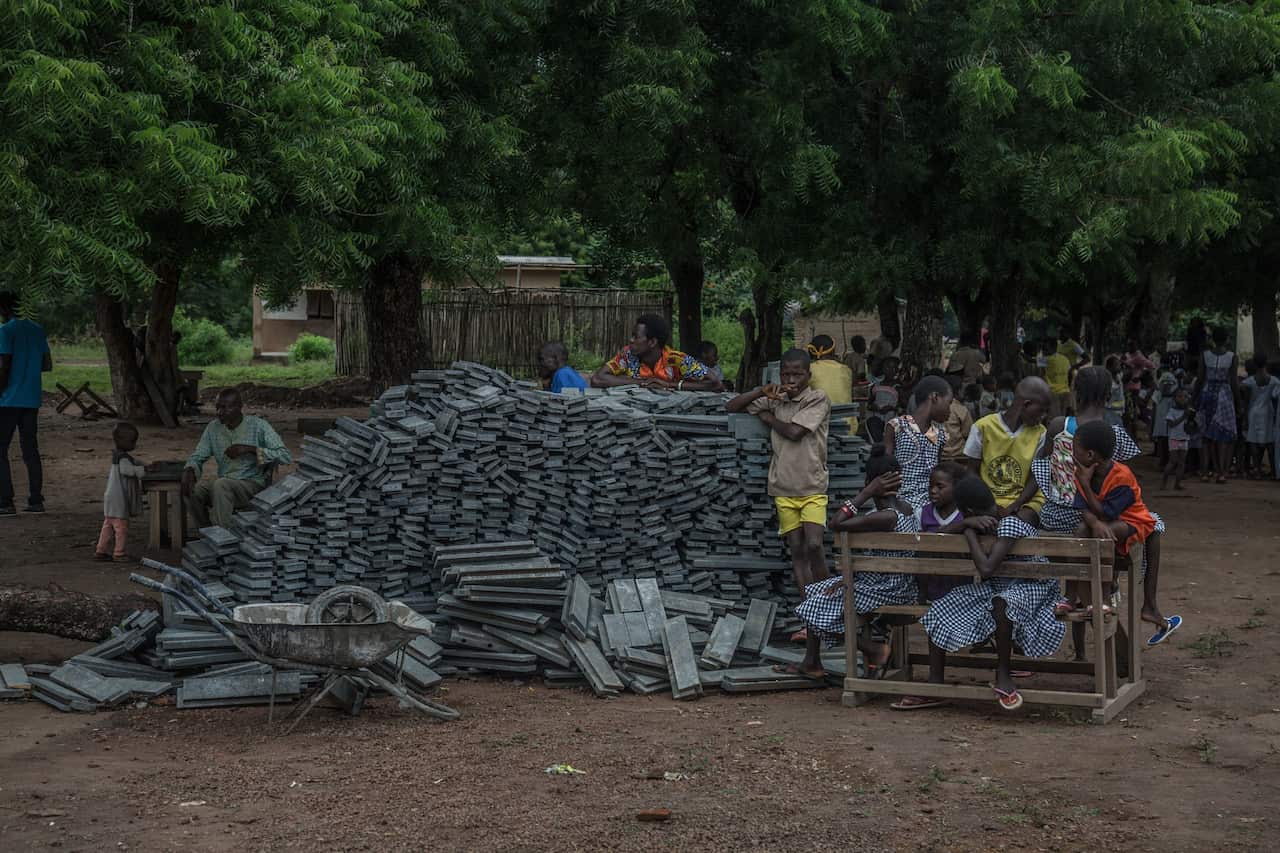Students and residents gathered by plastic bricks outside their school in the Sakassou village.