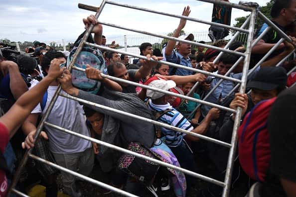 Honduran migrants remove a barrier at the Guatemala-Mexico international border bridge.