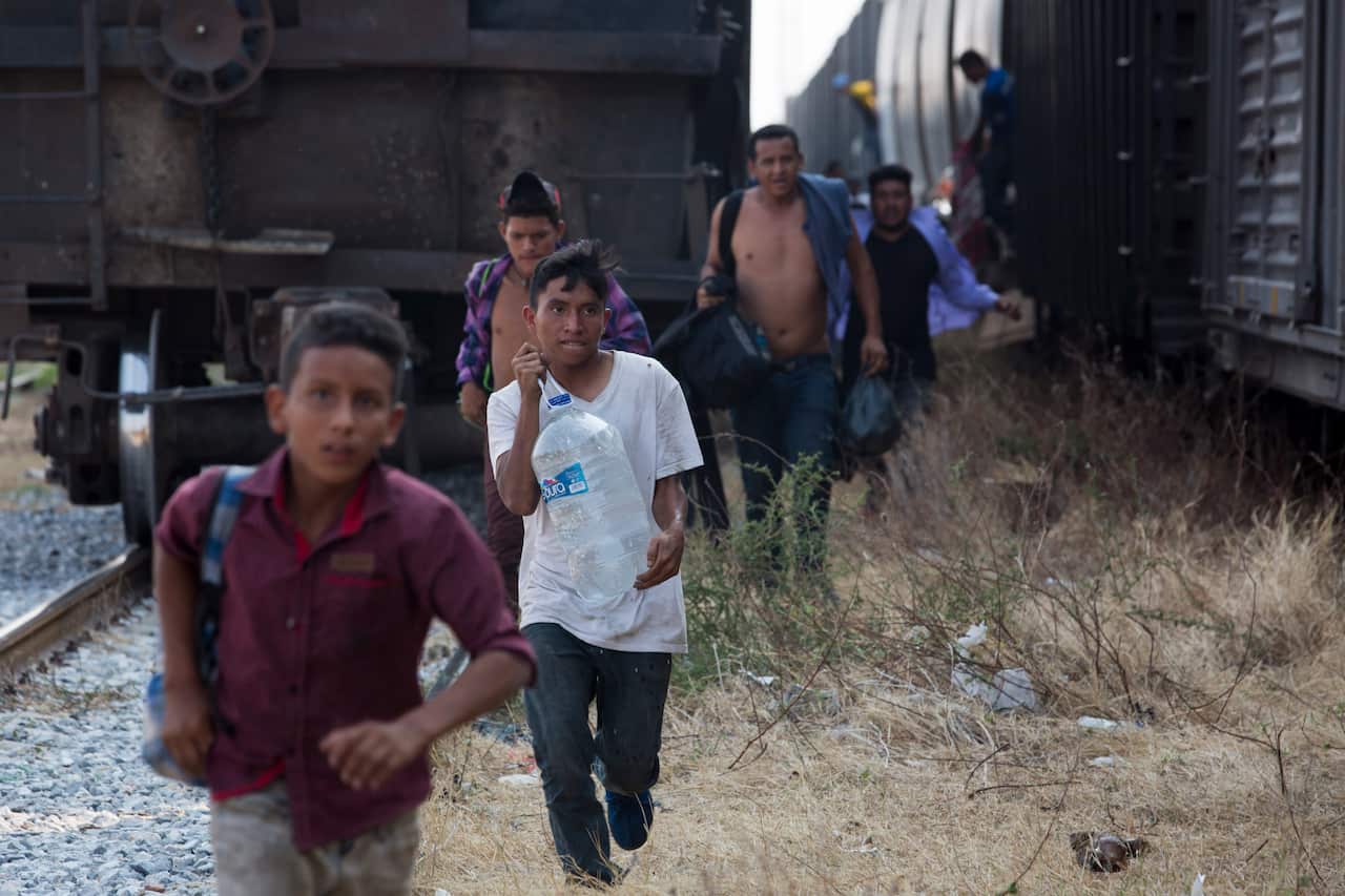 Central American migrants run for a parked train during their journey toward the US-Mexico border, in Ixtepec, Oaxaca state, Mexico.