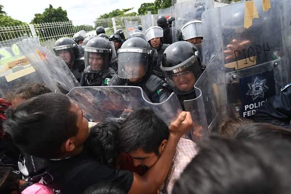 Mexican Federal Police officers try to prevent Honduran migrants from crossing the border.