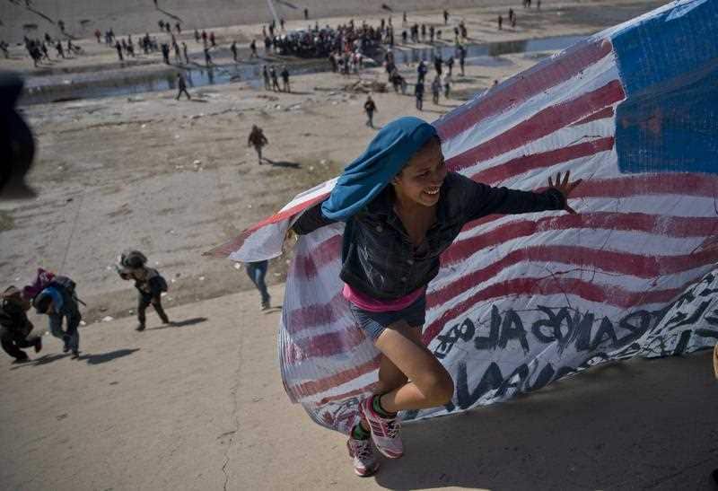 Migrants cross a riverbed at the Mexico-U.S. border after getting past a line of police at the Chaparral border crossing in Tijuana.