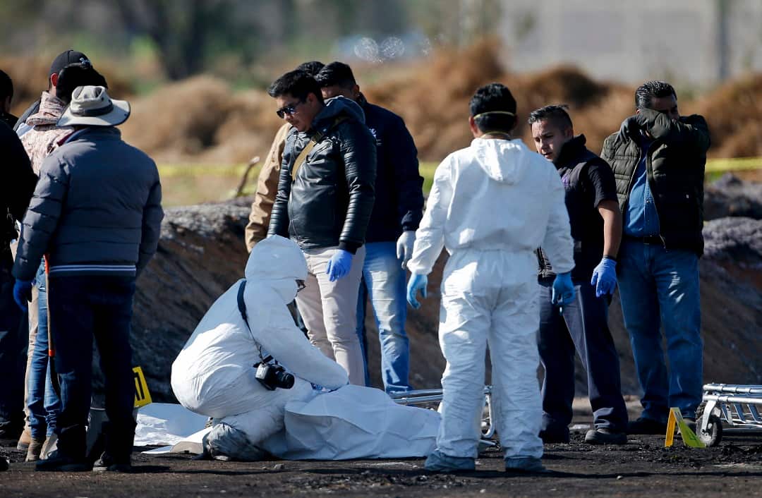 Forensic teams examine the bodies of people killed by an explosion.