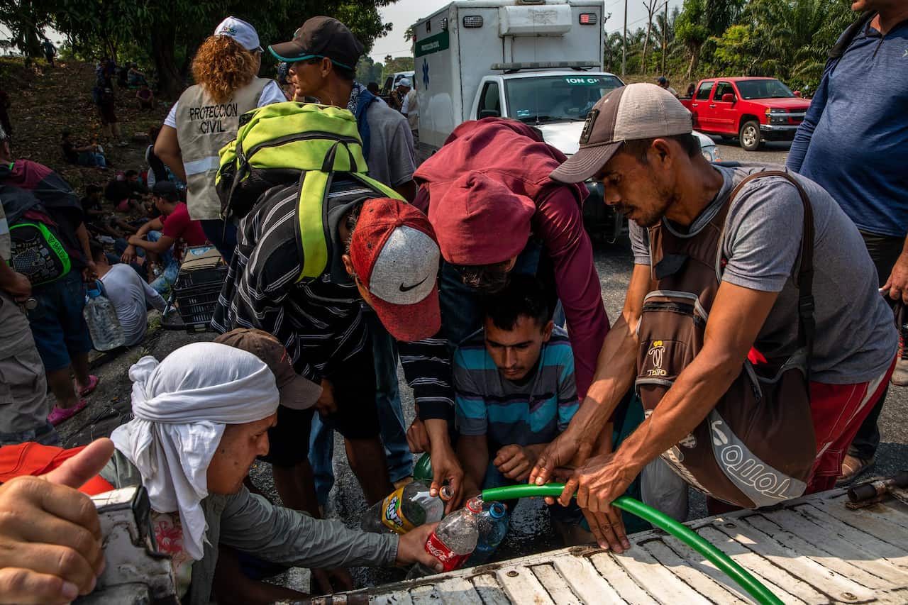 Migrants collect water while walking north through the Mexican state of Chiapas, Mexico, near the town of Huixtla.
