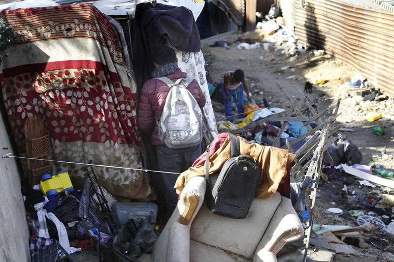 A local man steps out of his shanty on the Mexican side of the border next to the structure that separates Mexico and the United States, in Tijuana.