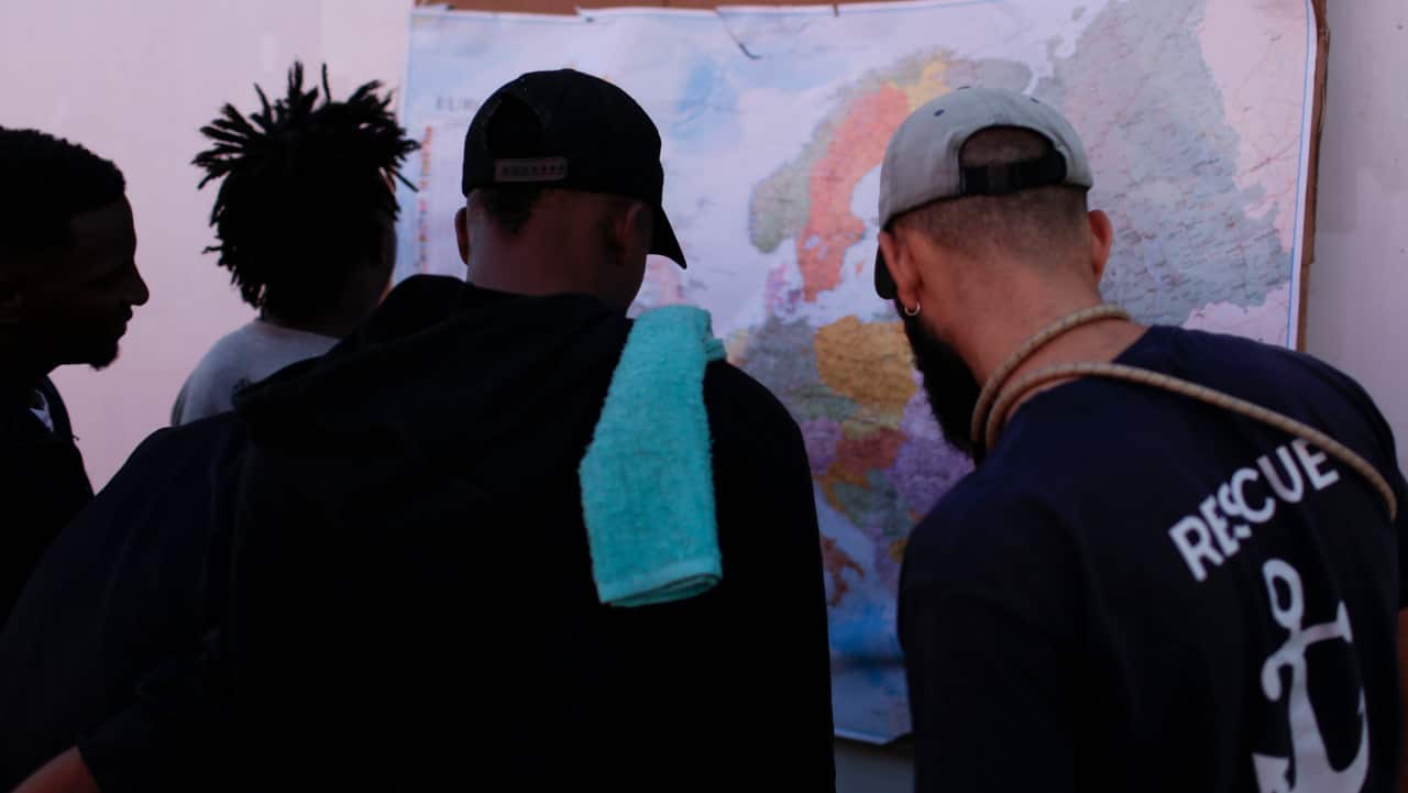 Men look at a map of Europe aboard the Ocean Viking in the Mediterranean Sea.