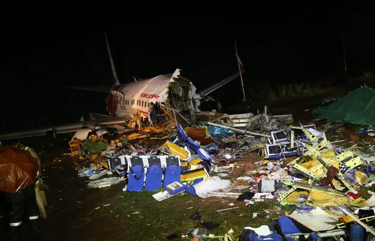Officials stand near the wreckage site of a plane crash at Calicut International Airport in Kozhikode, India, 08 August 2020. 