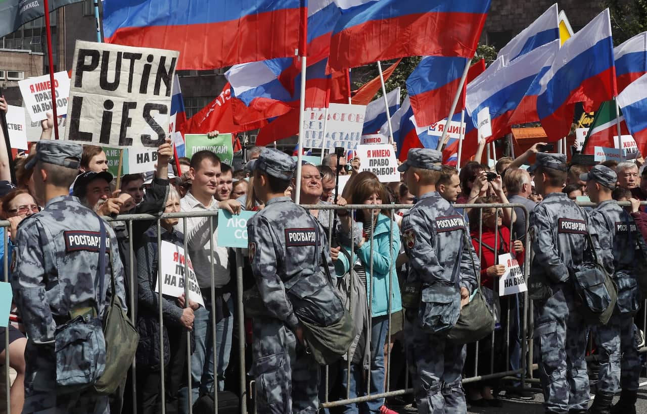 Russian opposition supporters hold a poster 'Putin lies' during a rally in support of opposition candidates in the Moscow City Duma elections