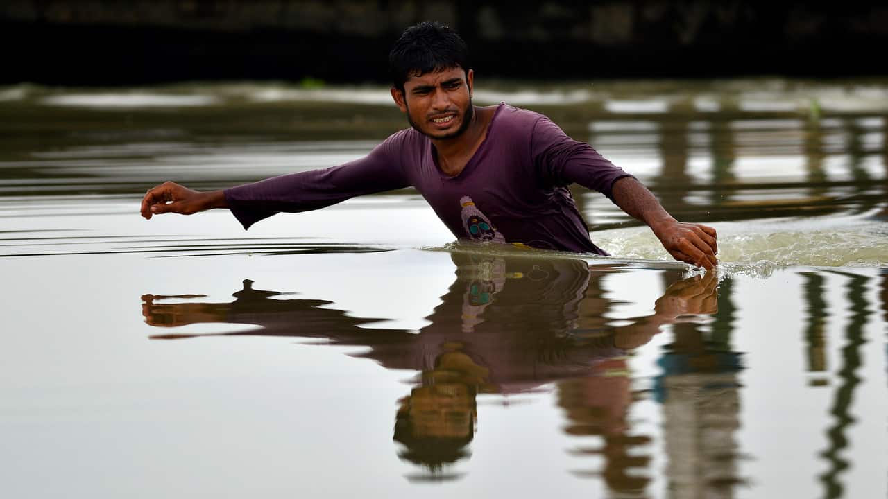 A man searches for his belongings in flood waters in the flood affected Morigaon district of Assam, India, 12 July 2019.