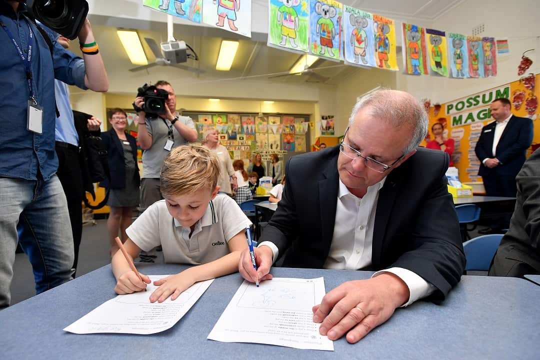 Prime Minister Scott Morrison does some class work during a visit to Galilee Catholic Primary School to spruik a $4.6 billion funding deal. 