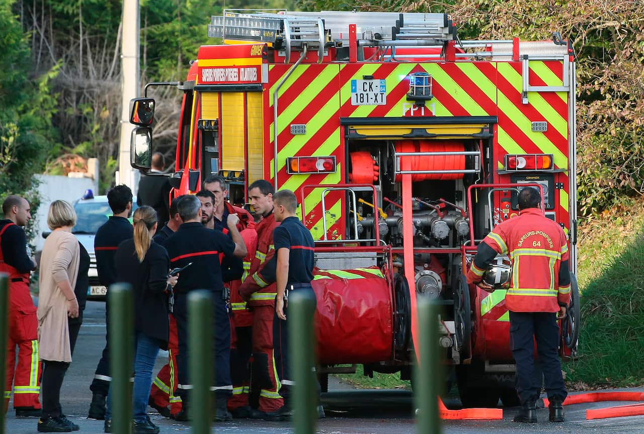 Local residents and firemen stand next to a fire truck after the attempted arson. An elderly man has now been charged.