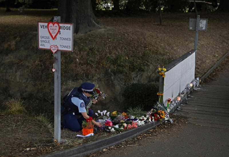 A police officer drops off flowers at a park outside the Masjid Al Noor mosque in Christchurch ahead of the funeral.