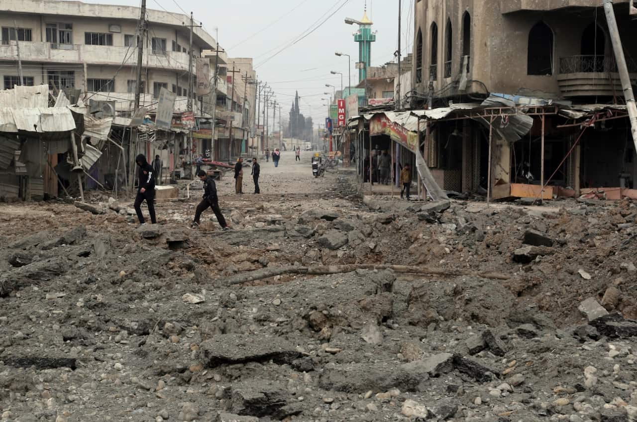 FILE: Civilians walk amid the rubble after a fight between Iraqi security forces against Islamic State militants in Mosul, Iraq. 