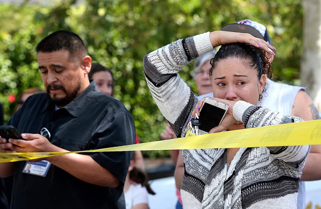 Parents and family of North Park Elementary School students stand across the street from the school waiting to hear from their children