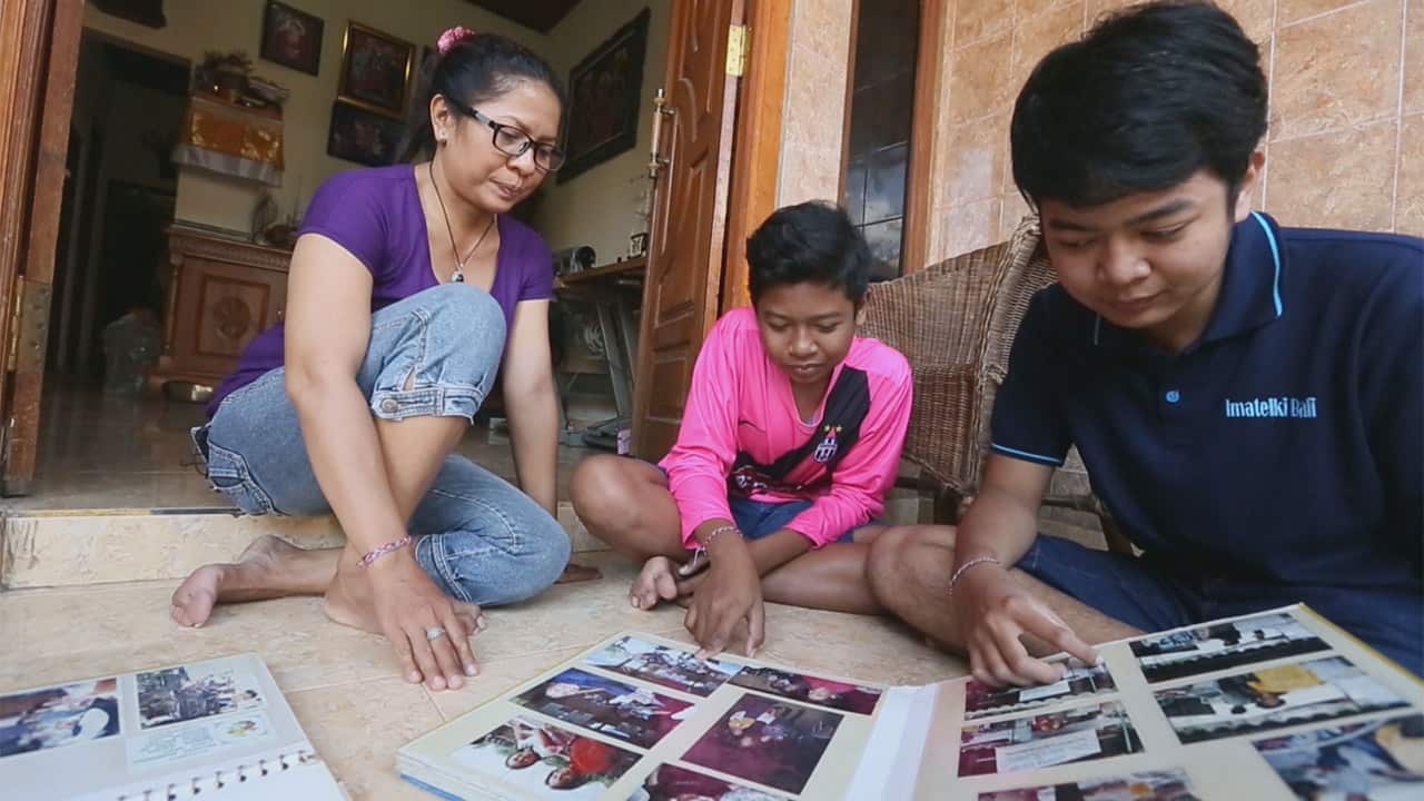 Ni Luh and her children now, looking through family photos.