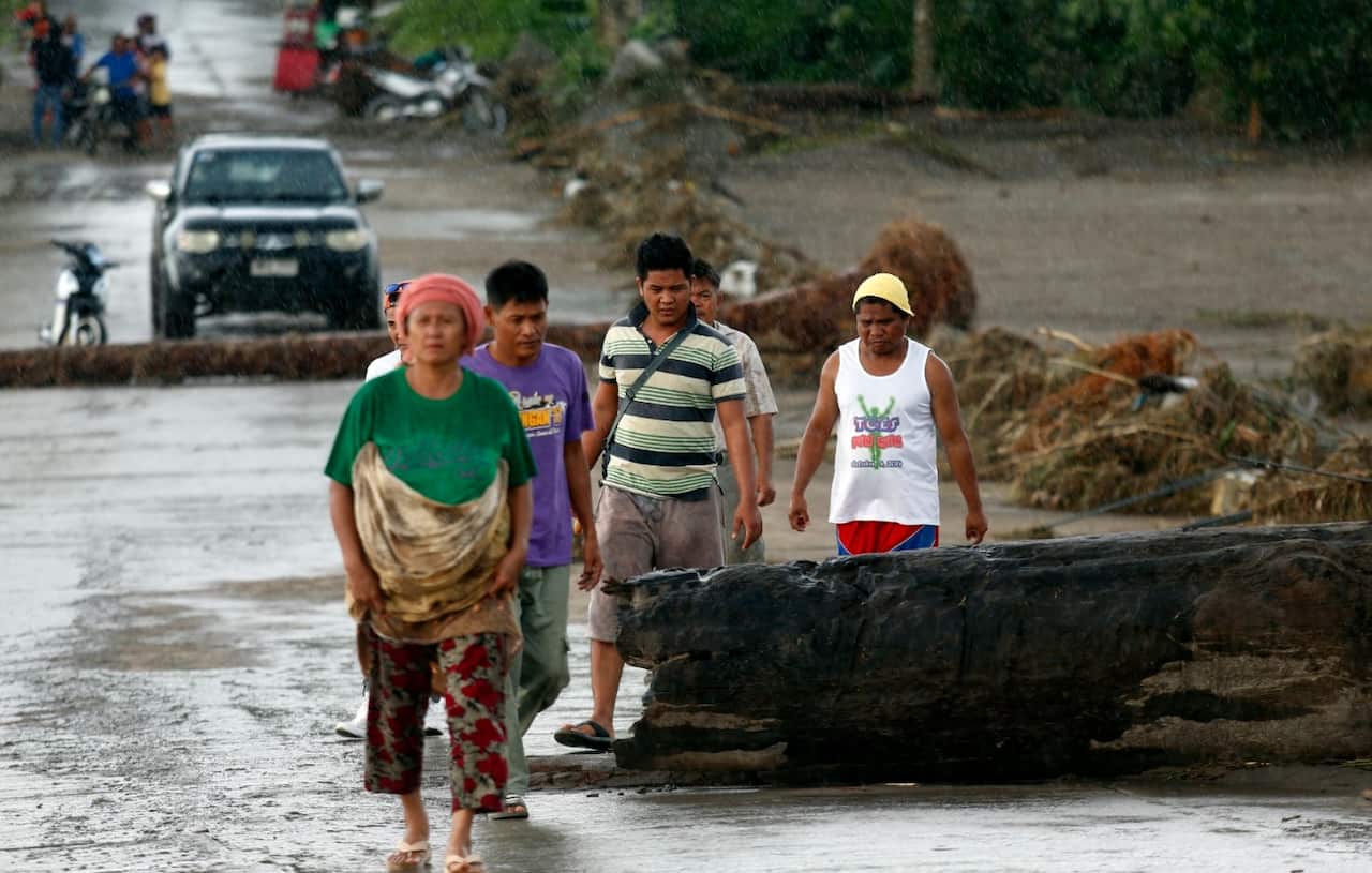 Filipino villagers walk amongst debris in flood hit town of Salvador, Lanao del Norte province, Philippines, 23 December 2017. 