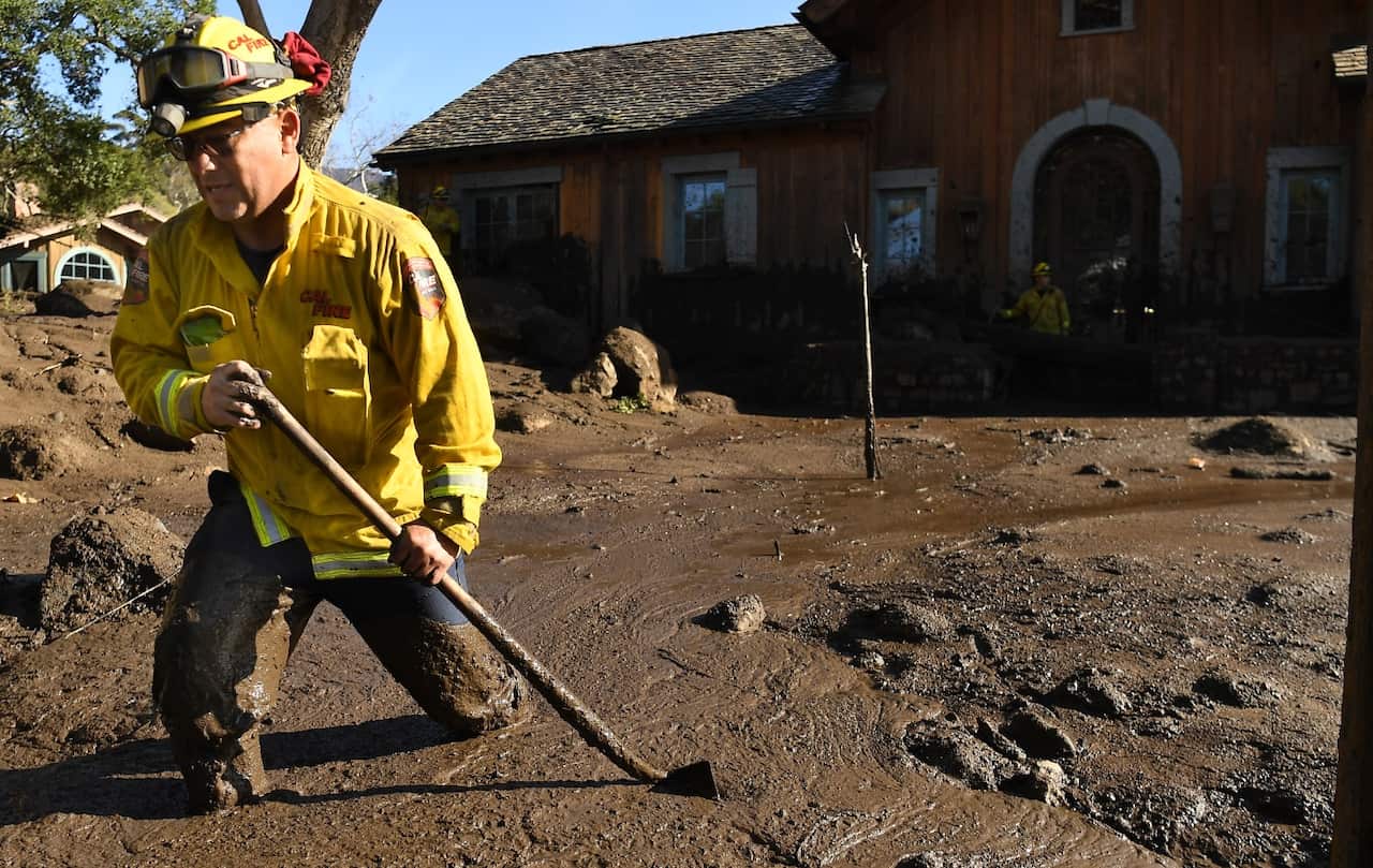 Cal Firefighter Alex Jimenez walks out after marking a spot with a stick where he found a body under the mud at a house along Glen Oaks Drive