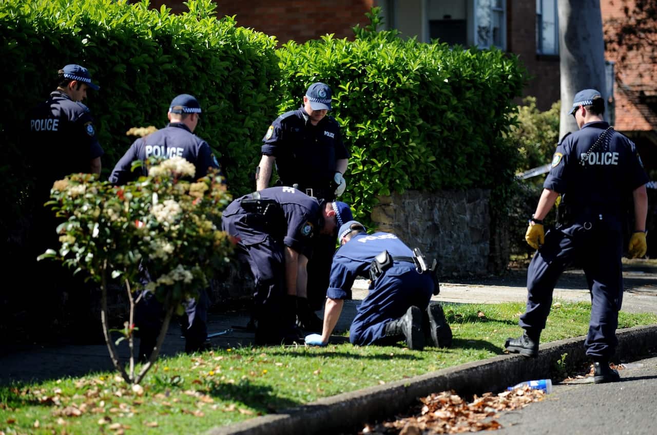 Police officers search the street for evidence following the shooting death of property developer Michael McGurk in Sydney, Friday, Sept. 4, 2009.