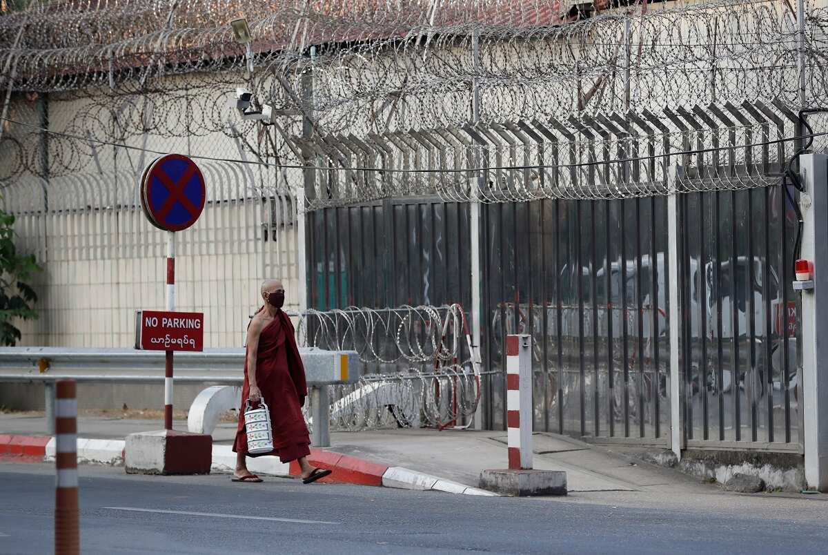 A Buddhist monk walks pass near the blocked platform in front of Russian embassy in Yangon after a protest against the military coup.