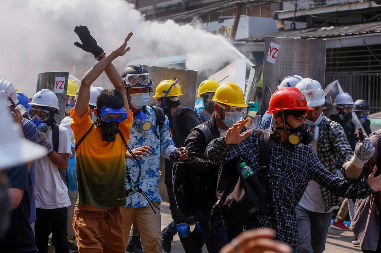 Anti-coup protesters retreat from the frontlines after policemen fire sound-bombs and fire with rubber bullets in Yangon, Myanmar.