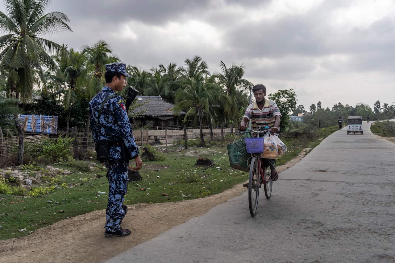 A border guard watches a Rohingya man at a checkpoint in the Muslim quarter of Maungdaw, in Myanmar's Rakhine State, 