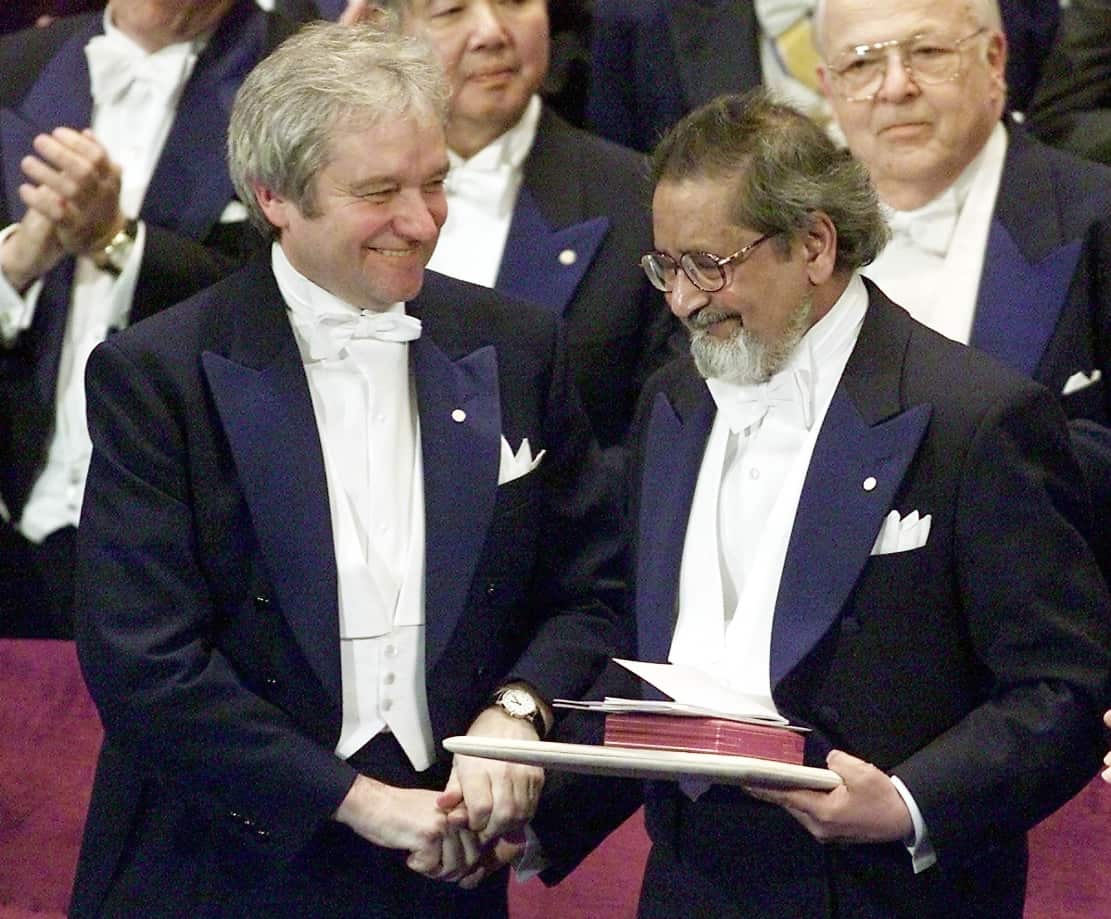 Britain's Sir Paul Nurse (L) shakes the hand of Sir VS Naipaul after Naipaul received the Nobel Prize in Literature