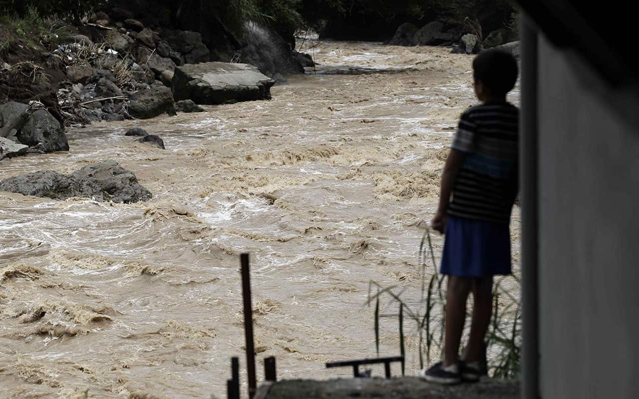 A child looks at the river where the collapse of an embankment destroyed several houses after the passage of the tropical storm Nate.