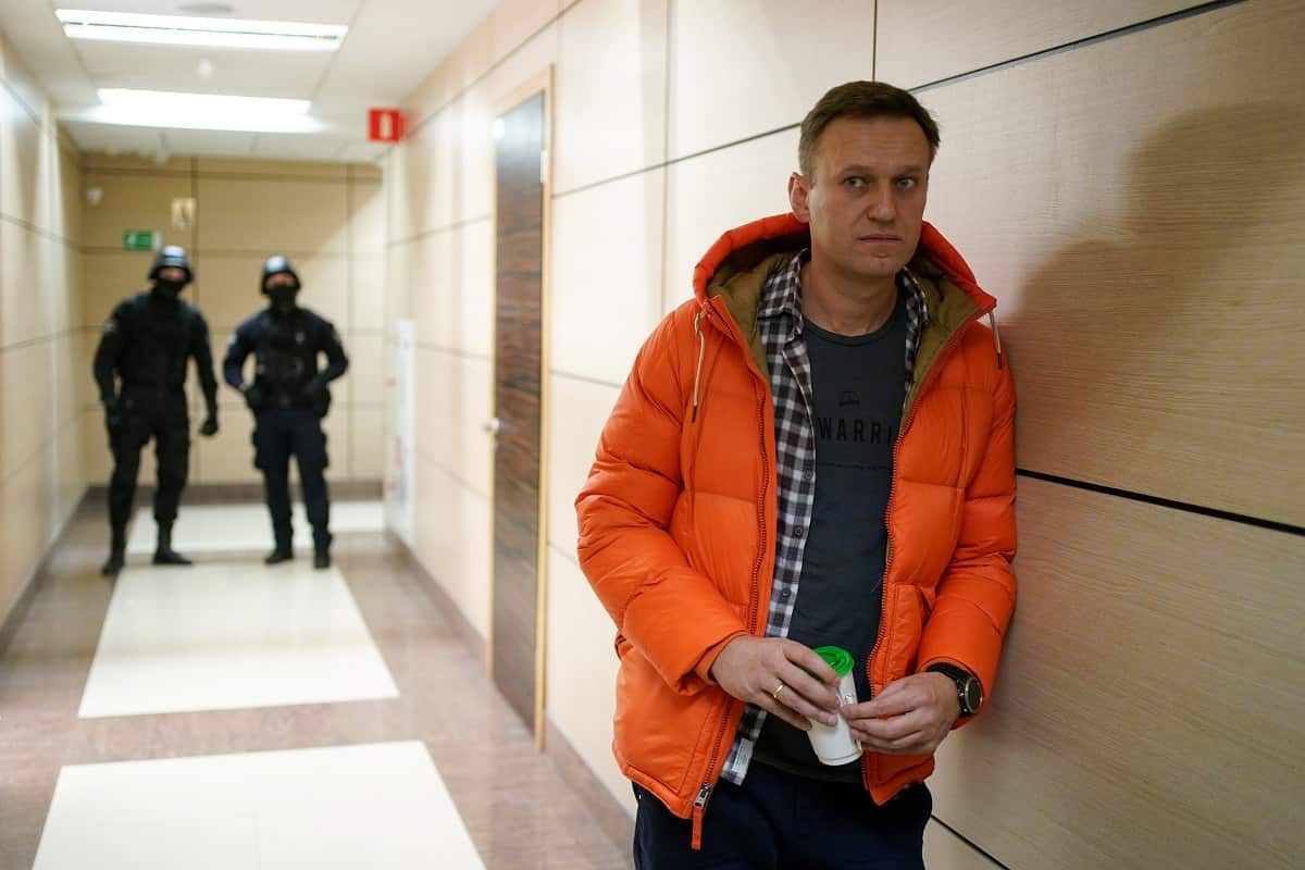 Russian opposition leader Alexei Navalny stands near law enforcement agents in a hallway in Moscow on December 26, 2019. 