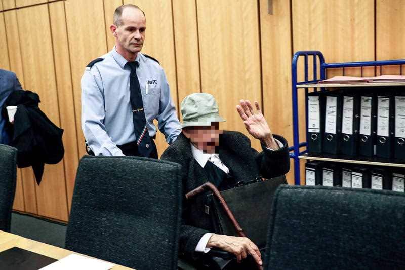 The accused Nazi guard is wheeled out of the court. He denies knowing anything about atrocities committed during the war.