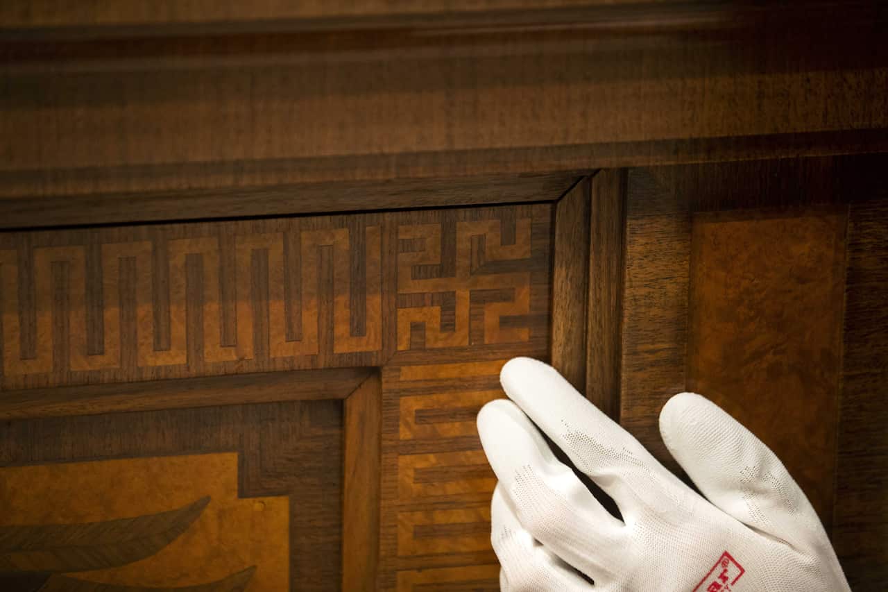 A museum employee points out a swastika on the side of Hitler’s sideboard, which is featured in the exhibition.