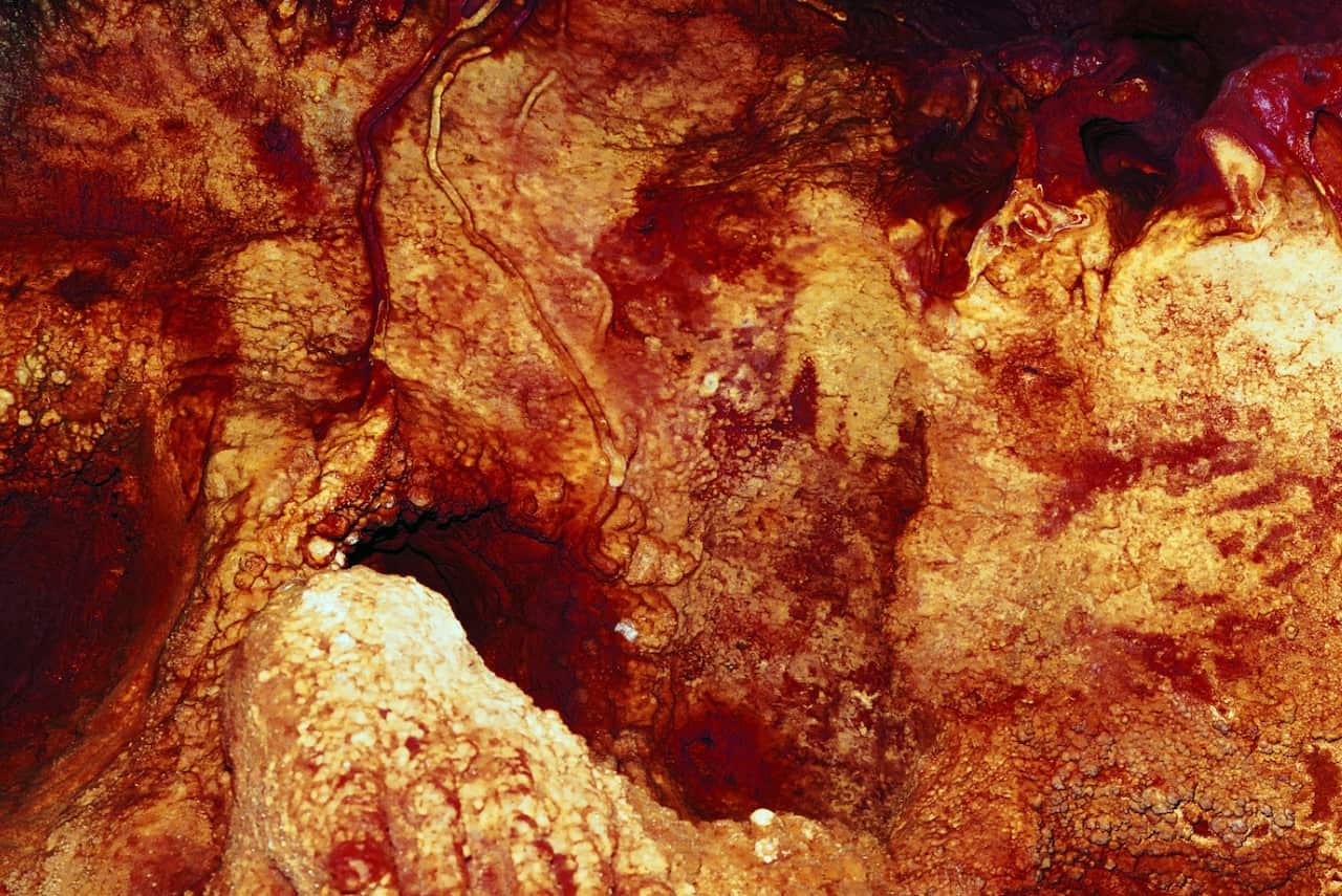 This color enhanced image provided by Hipolito Collado Giraldo in February 2018 shows three hand stencils in the Maltravieso Cave 
