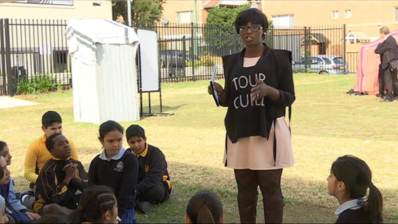 Tour guide and Sierra Leone refugee, Marie Sesay, shares her story with primary school students. (SBS)