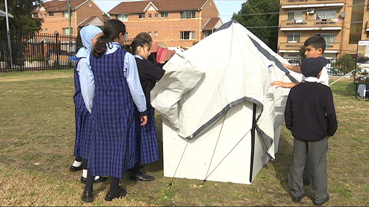 Children build a shelter at the interactive refugee camp learning experience in Auburn (SBS)