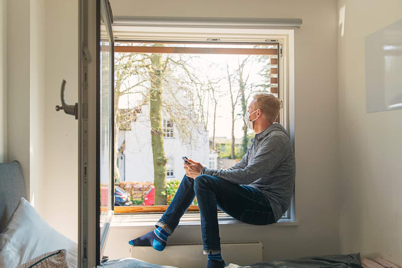 Man with mask looking out of window