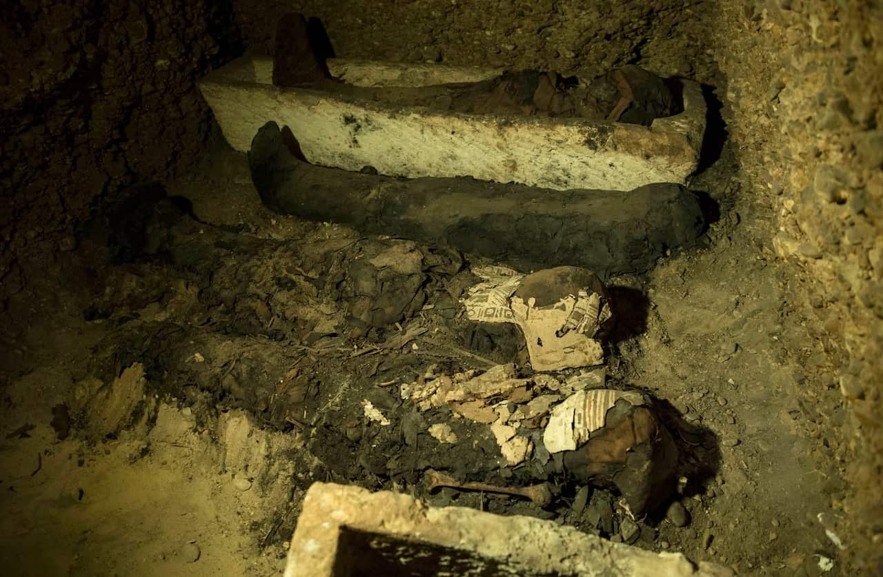 Mummies and other artifacts lie in a recently discovered burial chamber in the desert province of Minya