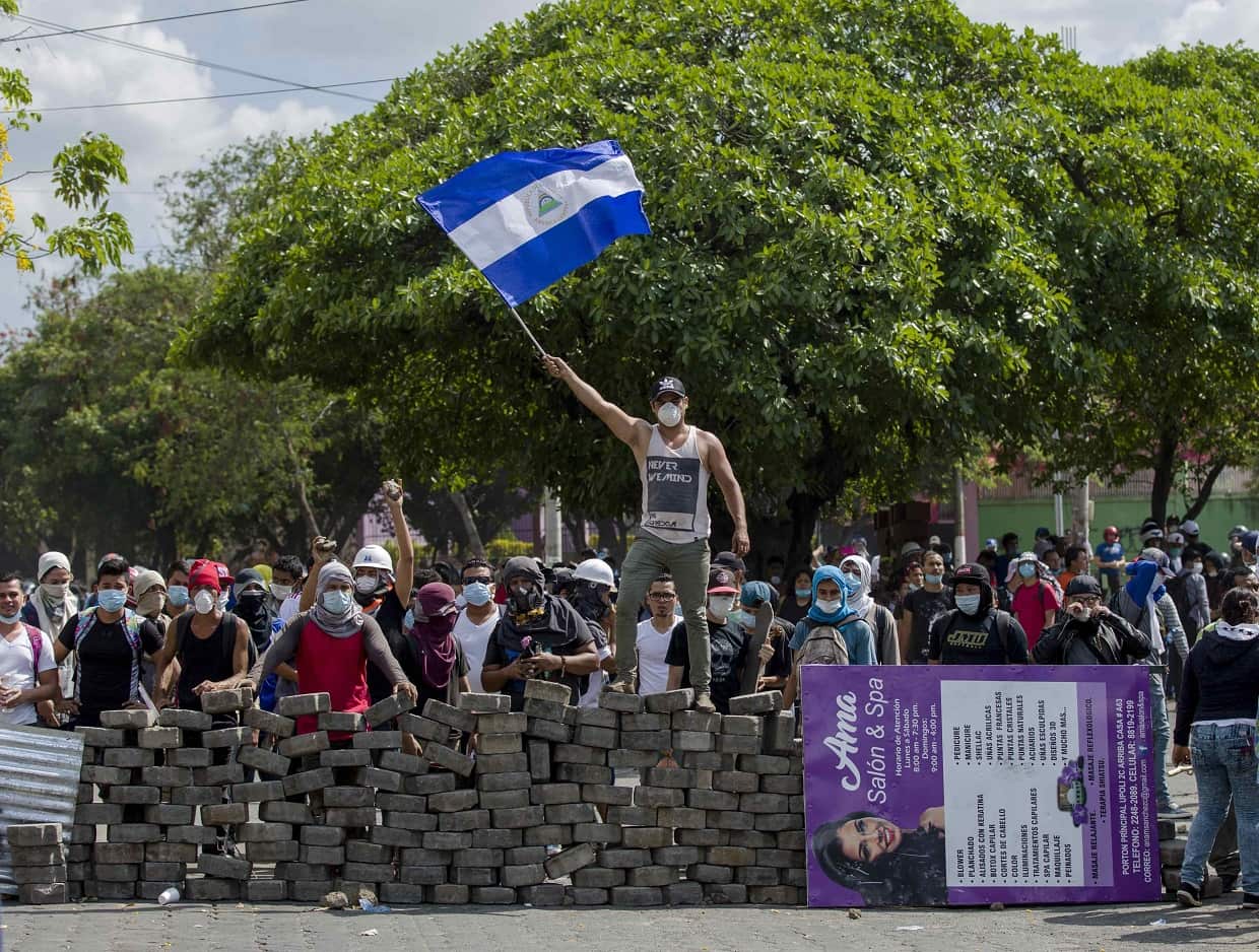 A young man raises a Nicaraguan national flag on a cobblestone barricade in Managua, Nicaragua, on April 21. 