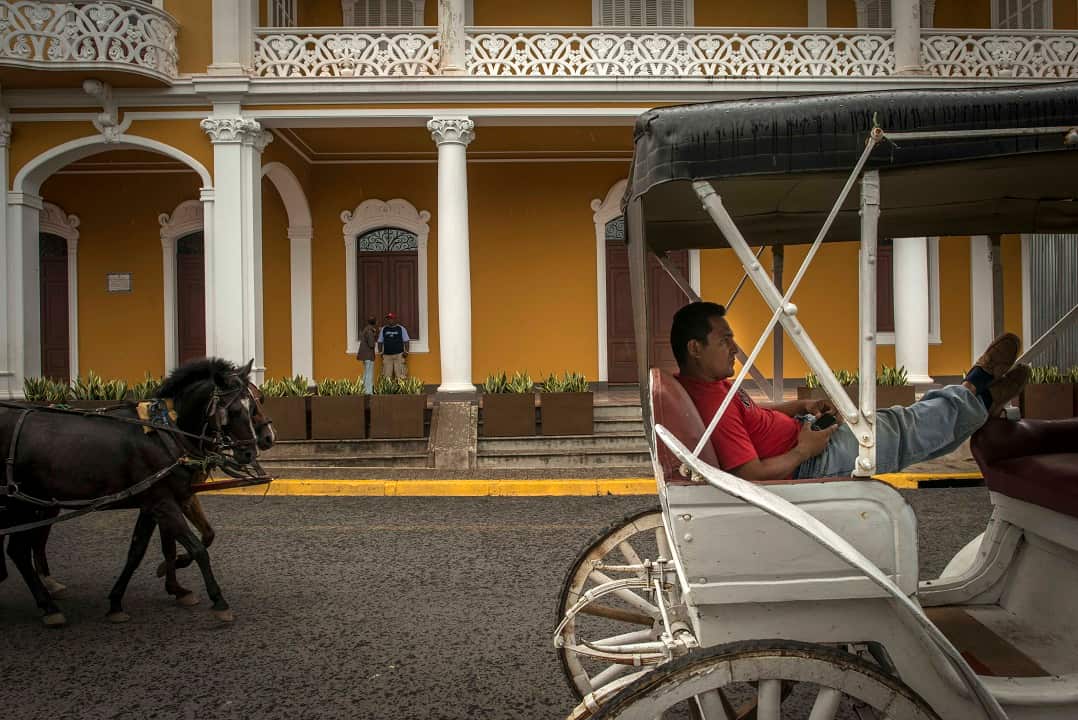 A man reclines in his horse-drawn carriage on a quiet day in Granada, Nicaragua.