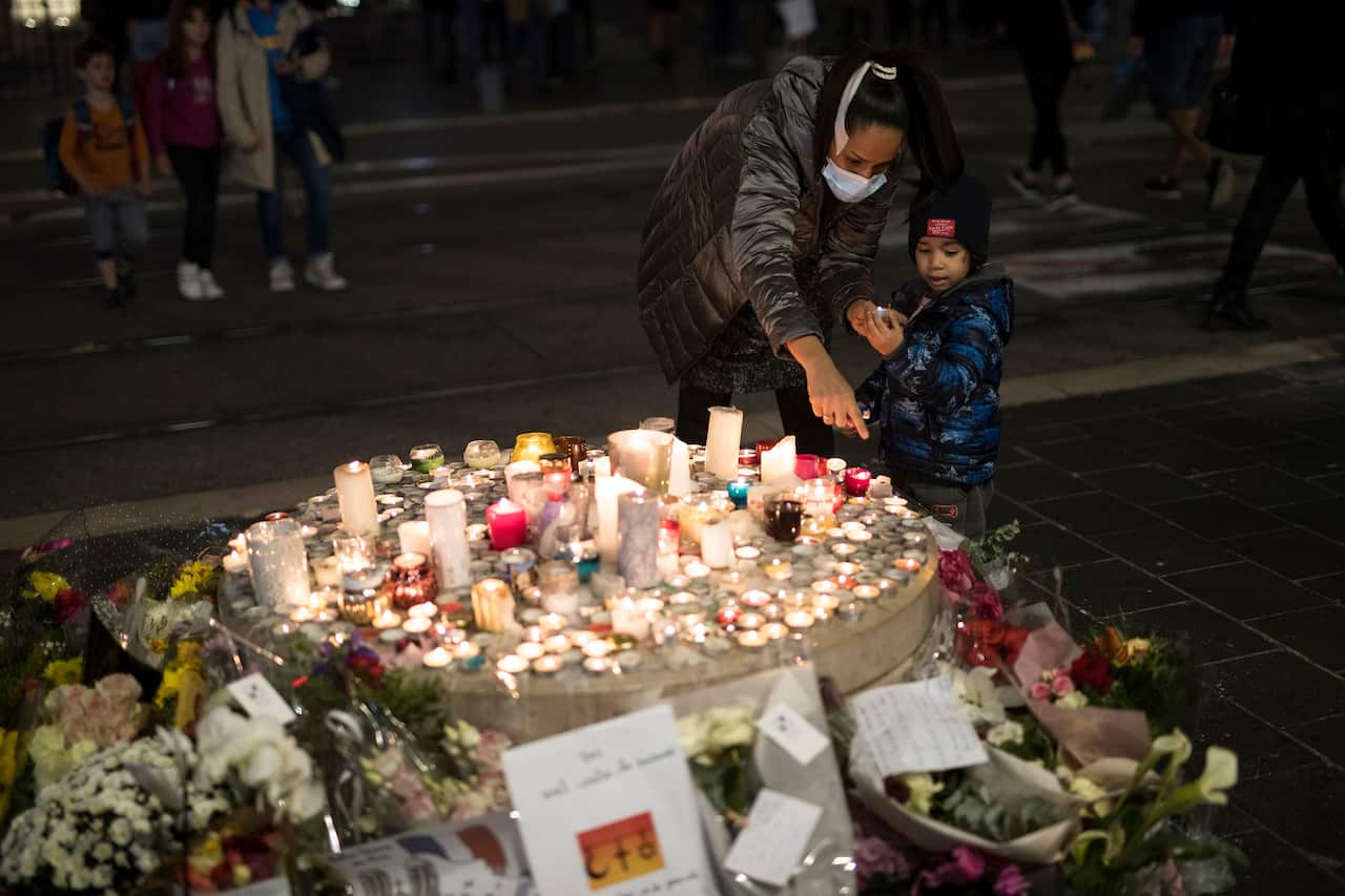 A family lights a candle in front of the Notre Dame church in Nice, France.