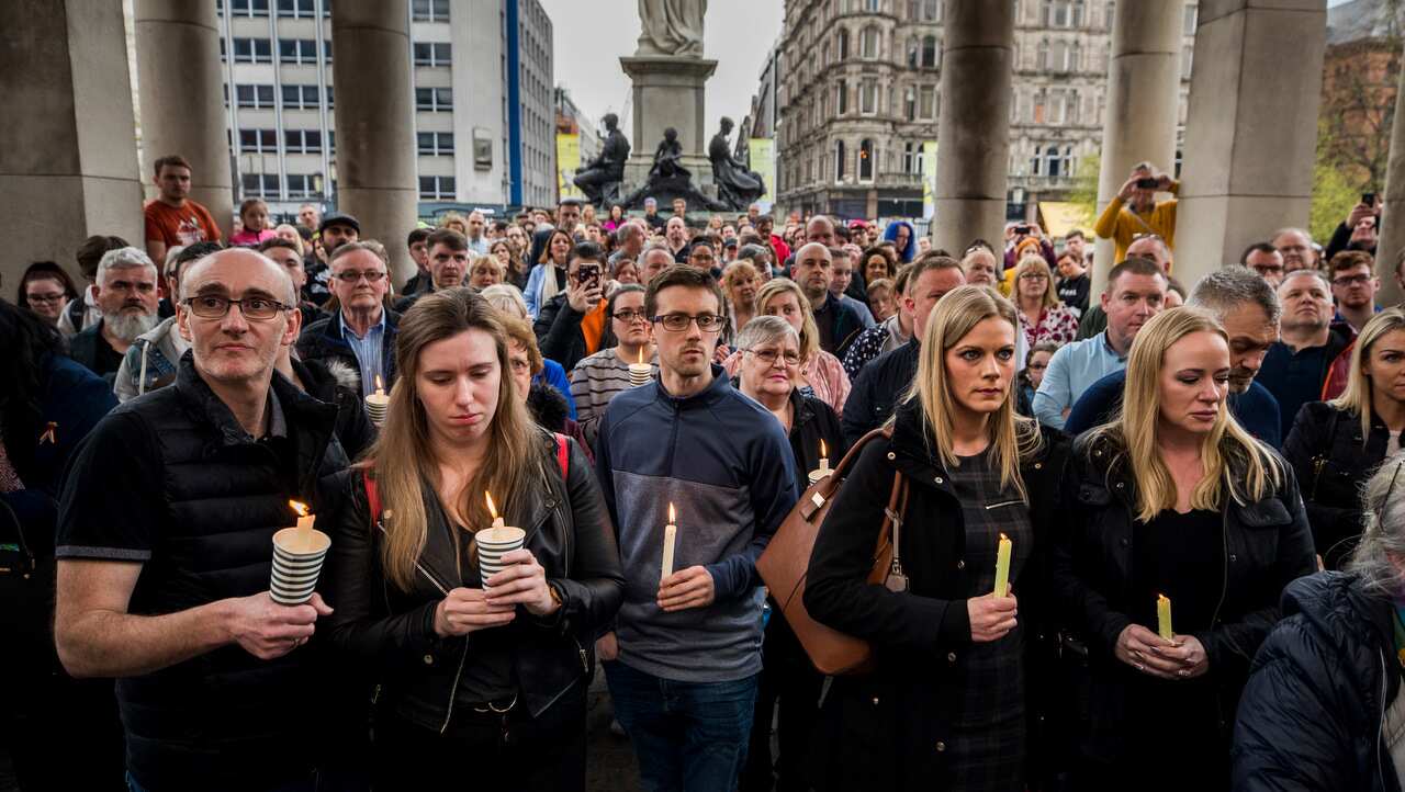 People hold candles during a vigil at Belfast City Hall in memory of murdered journalist Lyra McKee.