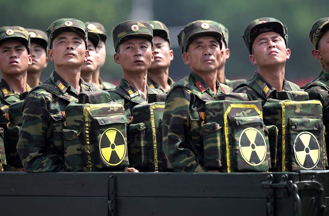 North Korean carry packs marked with the nuclear symbol during a parade.