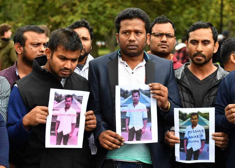 Friends of a missing man Zakaria Bhuiyan hold up photos of him outside a refuge centre in Christchurch.