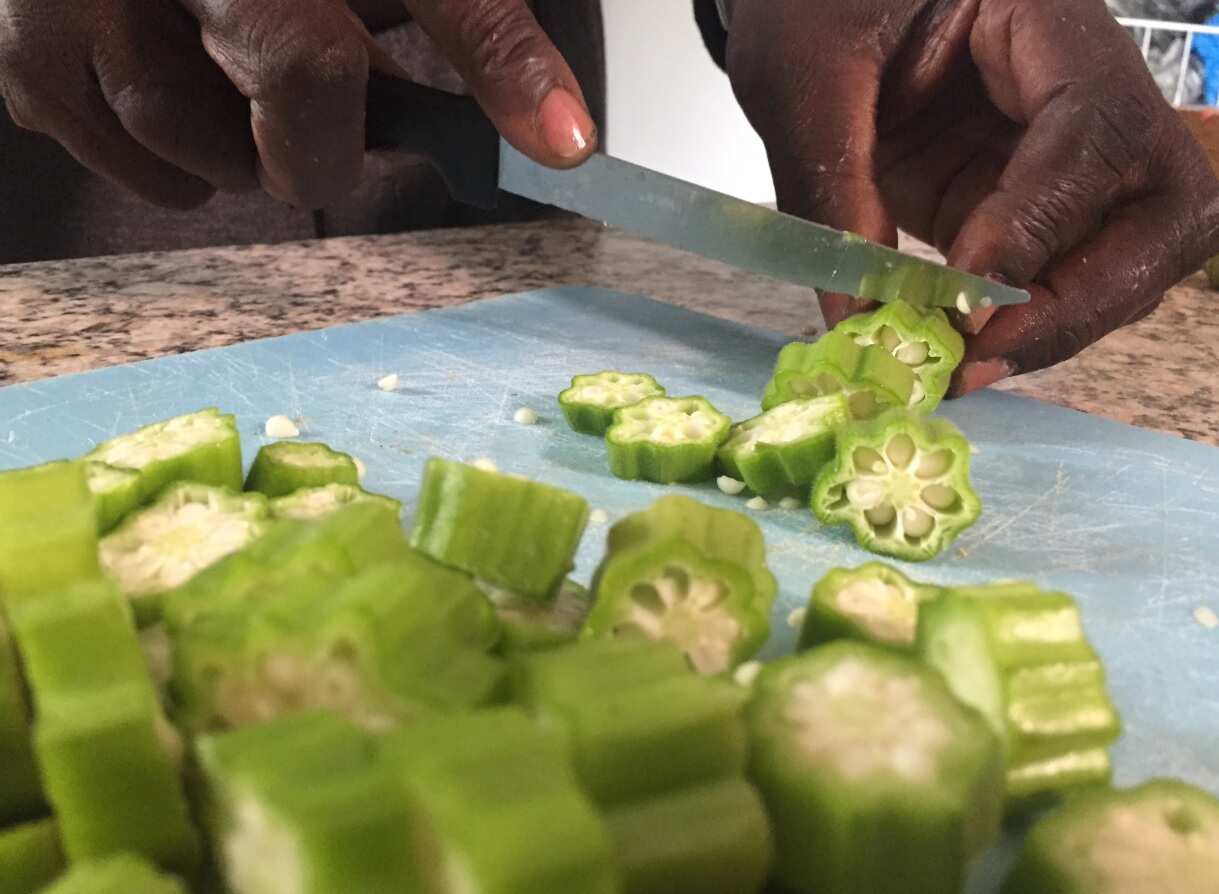 South Sudanese Dinka man Mana Athian chops okra grown in his back yard in Brisbane.