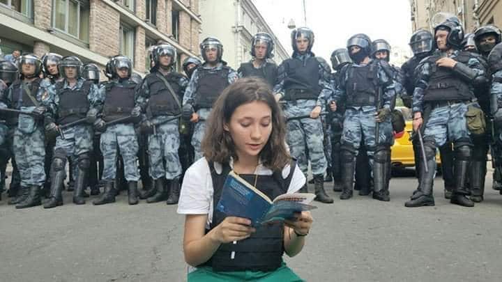 A 17 year -old Russian girl is being hailed as a hero and symbol of resistance after she was photographed reading the Russian constitution to a group of armed riot police at a bloody protest.
